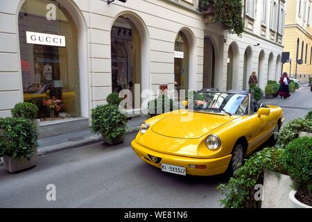 L'Italie, Lombardie, Milan, Quadrilateral (quadrilatero della moda), Alfa Romeo Spider Duetto cabriolet jaune en face de la boutique de luxe Gucci via Santo Spirito Banque D'Images