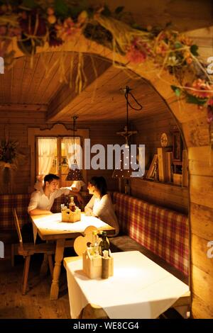 Italie, province autonome de Bolzano, San Candido, jeune couple installé dans une alcôve de la pizzeria helmhotel installés dans la décoration boisée d'une ancienne bergerie Banque D'Images