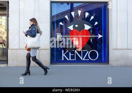 France, Paris, femme marche par la fenêtre avant de Kenzo shop à la place de la Madeleine Banque D'Images