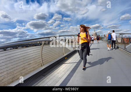 Londres, Angleterre, Royaume-Uni. Jeune femme traversant le pont du millénaire sur une journée ensoleillée en Août Banque D'Images