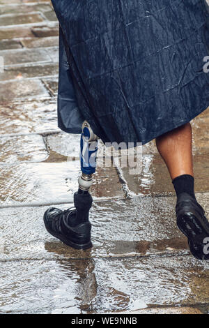 L'homme actif ou pèlerin avec une prothèse marche sur une rue de la vieille ville de Santiago de Compostela sur un jour de pluie. Personne handicapée positive Banque D'Images