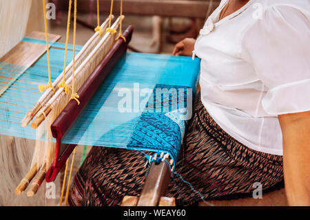 Femme Asiatique travaillant sur métier à tisser en bois vintage avec des fibres de soie, tissage, travail de l'artisanat de l'outil. Concept du tourisme culturel Banque D'Images