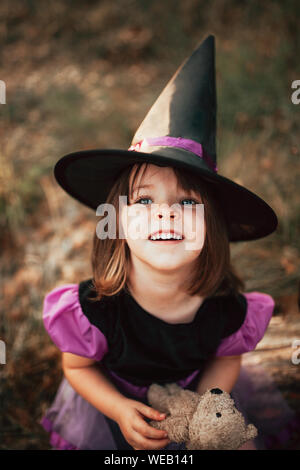 Smiling girl déguisée comme une sorcière dans les bois à l'Halloween Banque D'Images