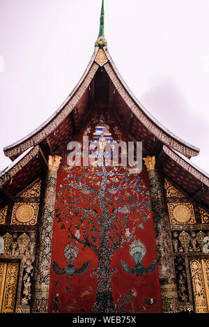 Golden Buddha et l'art mural Mur mosaïque 'Arbre de vie' au hall principal du Wat Xieng Thong, Luang Prabang, Laos Banque D'Images