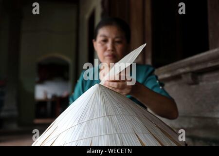 (190830) -- HANOI, 30 août 2019 (Xinhua) -- une femme fixe les feuilles de palmier sur un cône de bambou pour faire un Chapeau conique traditionnel dans le Chuong village à la périphérie de Hanoi, capitale du Vietnam le 29 août, 2019. Traditionnel du Vietnam, chapeaux coniques sont à base de bambou et de feuilles de palmier, et ils sont parmi les plus impressionnants costumes traditionnels. Les gens dans le village Chuong ont fait des chapeaux coniques pour environ 400 ans. Les sections locales acheter vert feuilles de palmier d'autres provinces, les sécher au soleil et le fer et l'eau de javel les feuilles en tranches. Ils utilisent ensuite les cordes minces de fixer l Banque D'Images