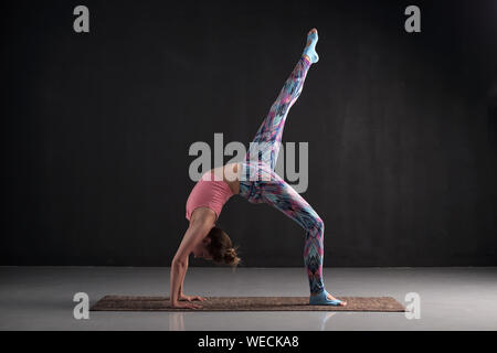 Femme pratique le yoga asana eka pada chakrasana ou dhanurasana ou poser des roues à une jambe. Studio shot Banque D'Images