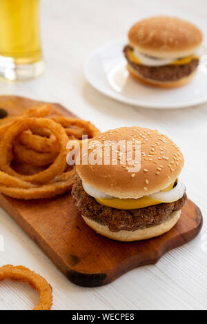 Des limaces Mississippi hamburgers avec des oignons et un verre de bière froide sur une surface en bois blanc, vue de côté. Close-up. Banque D'Images