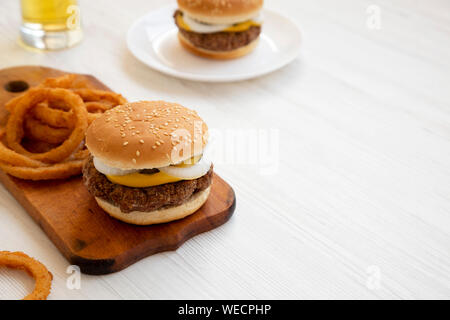 Des limaces Mississippi hamburgers avec des oignons et un verre de bière fraîche sur un fond en bois blanc, vue de côté. Copier l'espace. Banque D'Images