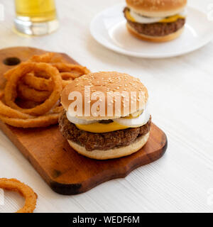 Des limaces Mississippi hamburgers avec des oignons et un verre de bière froide sur une surface en bois blanc, vue de côté. Close-up. Banque D'Images