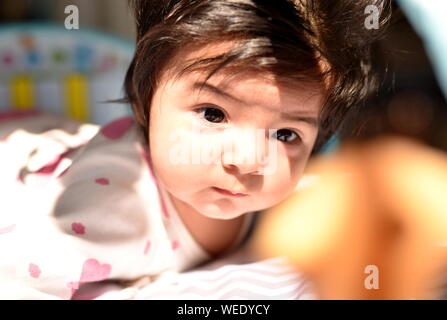 Cute hispanic girl regarde attentivement ses jouets en maternelle Banque D'Images