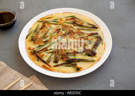 Coréen maison Pajeon scallion pancake sur une plaque blanche sur fond gris, vue de côté. La cuisine asiatique. Banque D'Images