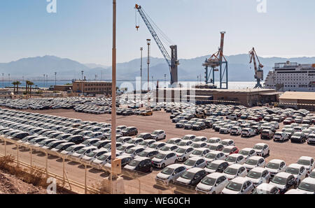 Une mer de nouvelles voitures en face des quais du port d'Eilat en Israël avec un bateau de croisière, les grues et les montagnes de Jordanie à l'arrière-plan Banque D'Images