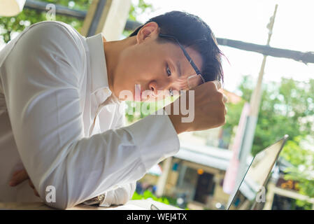 Frustrés Asian businessman working on laptop at cafeteria Banque D'Images
