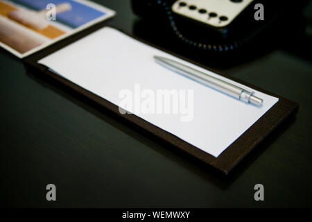 La couleur de plume d'argent est mis sur papier blanc courte note sur la table en bois brun près de téléphone dans la chambre d'hôtel de luxe Banque D'Images