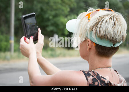 Hot blonde femme fait sur smartphone selfies sur fond d'un champ de tournesols, selective focus Banque D'Images