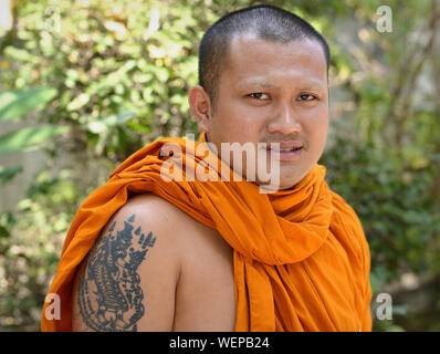 Jeune moine bouddhiste thaï avec un tatouage sur son bras supérieur droit sourire pour la caméra. Banque D'Images