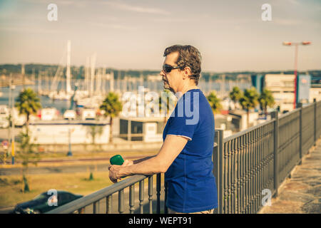 Homme debout et penser dans l'avenir s'appuyant sur une balustrade Banque D'Images