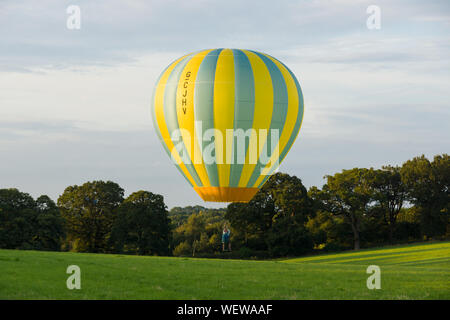 1-31 Série LTL Lindstrand hot air balloon solo d'atterrissage dans un champ le pilote est assis dans un siège au lieu d'un panier Banque D'Images