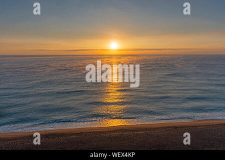 Lever de soleil sur une mer calme avec brouillard Banque D'Images
