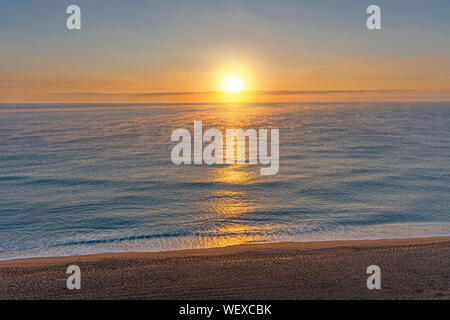Lever de soleil sur une mer calme avec brouillard Banque D'Images