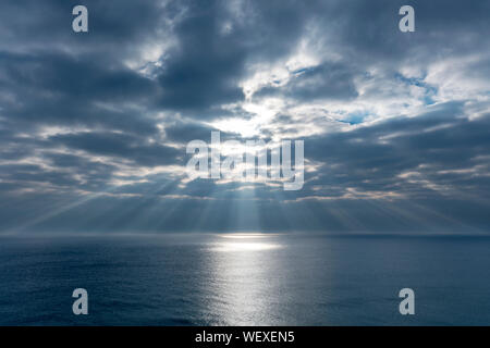 Du soleil À TRAVERS LES NUAGES AU-DESSUS DE LA MER Banque D'Images