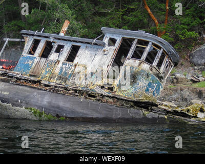 L'épave d'un vieux remorqueur en bois, le Kwatna, est une gîte sur sur la rive d'une île de Pender Harbour, sur la Sunshine Coast. Banque D'Images