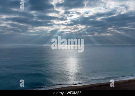 Du soleil À TRAVERS LES NUAGES AU-DESSUS DE LA MER Banque D'Images