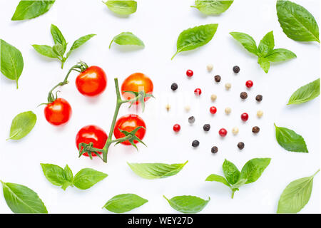 Tomates cerises fraîches avec des feuilles de basilic et de poivre de type différent sur fond blanc. Vue d'en haut Banque D'Images