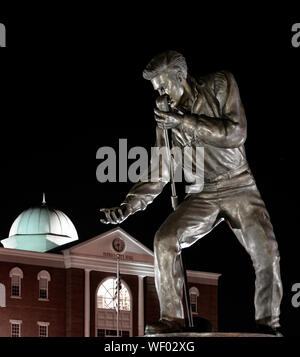 Elvis Presley statue en bronze posent avec microphone et de main tendue, dans la nuit, par l'Hôtel de Ville de Tupelo de Tupelo, MS, ETATS UNIS Banque D'Images