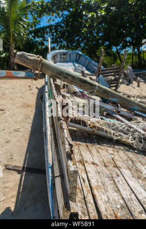 Point de vue de l'autre d'un bateau en bois bleu et abandonnés dans le sable de plage avec un mât lourd tombé sur elle, certains filets à l'intérieur et un Banque D'Images