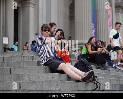 Ney York, NY / USA - Juin 28, 2019 : en faisant une pause sur les marches de l'avant avec d'autres touristes rencontrés le long Banque D'Images