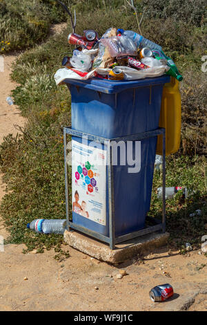 Poubelle débordante - sur une plage de l'Algarve au sud du Portugal. Banque D'Images