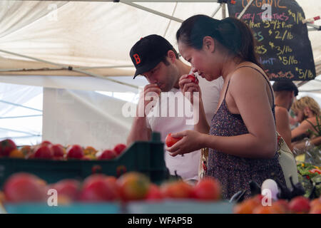 Un couple unique pour les tomates d'un examen attentif par l'odeur de morceaux à un marché de producteurs à Seattle, Washington, USA. Banque D'Images