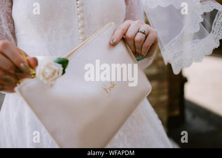 détail de la mariée le jour de son mariage tenant un sac d'embrayage avec la mariée écrit dessus Banque D'Images