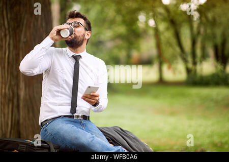 Pause de travail - young businessman sitting et de repos au parc. Banque D'Images