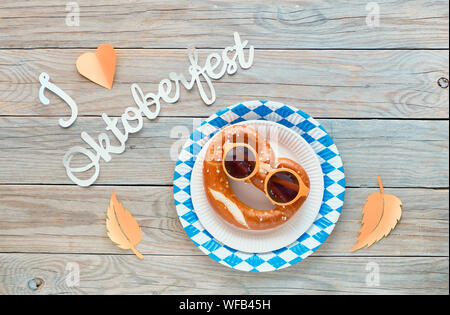 Texte papier 'J'aime' Oktoberfest, mise à plat sur une table en bois rustique avec les bretzels sur la plaque de papier décoratif avec les feuilles d'automne. Banque D'Images