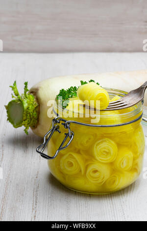 Daikon mariné sur fond blanc dans le bocal en verre Banque D'Images