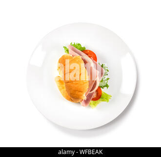 Big croissant avec une salade verte et la viande de porc sur isoler fond blanc. De délicieux croissants avec une fourchette et sombre à côté de la plaque photo alimentaire. Guérir Banque D'Images