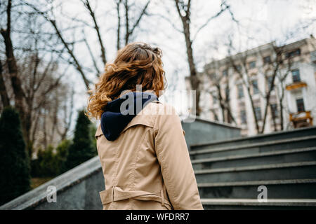 Une jeune femme en manteau beige monte les escaliers dans la ville Banque D'Images