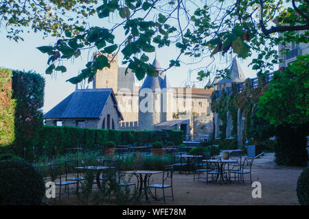 Vue du restaurant en plein air à La Cité de Carcassonne, ville médiévale, tours de guet et des murs en pierre. Ciel bleu, feuilles vertes et d'arbres. France, Europe Banque D'Images