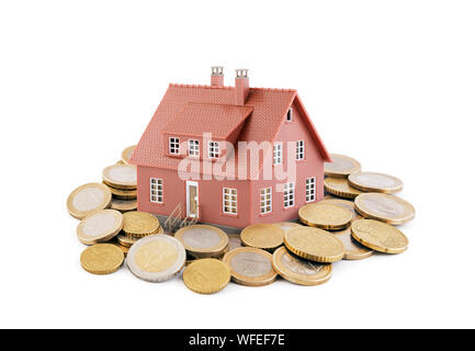 Petit brown toy house avec les pièces en euros sur fond blanc Banque D'Images