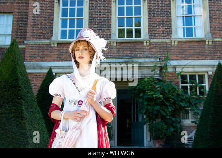 Belle dame portant robe et bonnet vintage regency, portant un parasol et à l'extérieur du gîte Banque D'Images