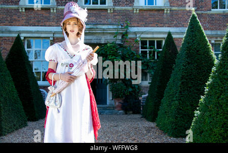 Belle dame portant robe et bonnet vintage regency, portant un parasol et à l'extérieur du gîte Banque D'Images