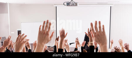 Portrait de personnes avec les bras levés dans la salle de conférences au cours de séminaire