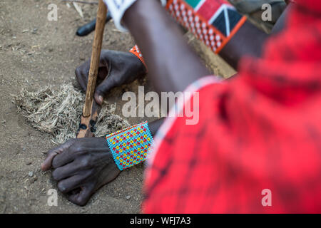 La tribu Masai man start incendie à l'aide de bouts de bois. Vl'à l'intérieur traditionnel du village le Parc national Amboseli, Kenya, Africa Banque D'Images