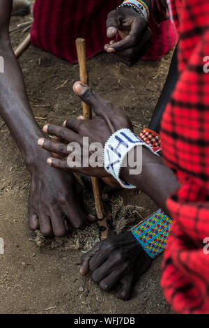 La tribu Masai man start incendie à l'aide de bouts de bois. Vl'à l'intérieur traditionnel du village le Parc national Amboseli, Kenya, Africa Banque D'Images