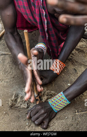 La tribu Masai man start incendie à l'aide de bouts de bois. Vl'à l'intérieur traditionnel du village le Parc national Amboseli, Kenya, Africa Banque D'Images