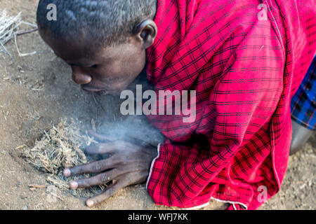 La tribu Masai man start incendie à l'aide de bouts de bois. Vl'à l'intérieur traditionnel du village le Parc national Amboseli, Kenya, Africa Banque D'Images