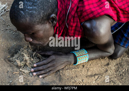 La tribu Masai man start incendie à l'aide de bouts de bois. Vl'à l'intérieur traditionnel du village le Parc national Amboseli, Kenya, Africa Banque D'Images