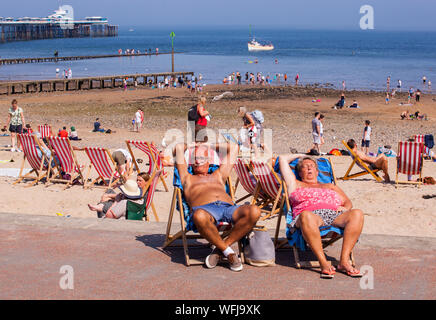 Homme âgé et femme endormi dans des chaises longues sur la promenade de la station balnéaire de Llandudno North Walespeople Banque D'Images